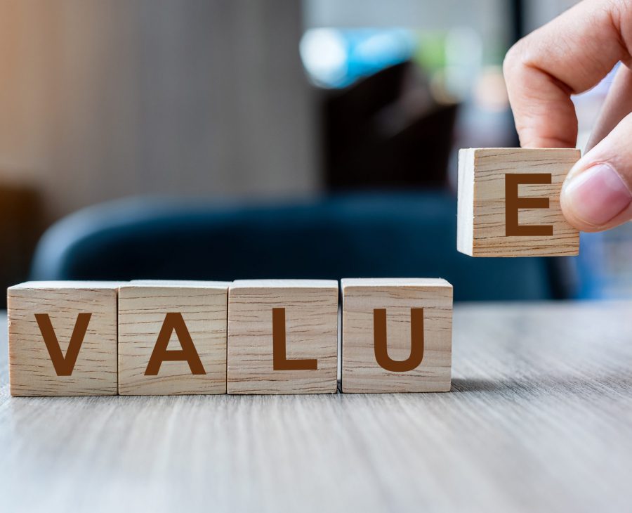 Businessman hand holding wooden cube block with Value business word on table background. Mission, Vision and core values concept